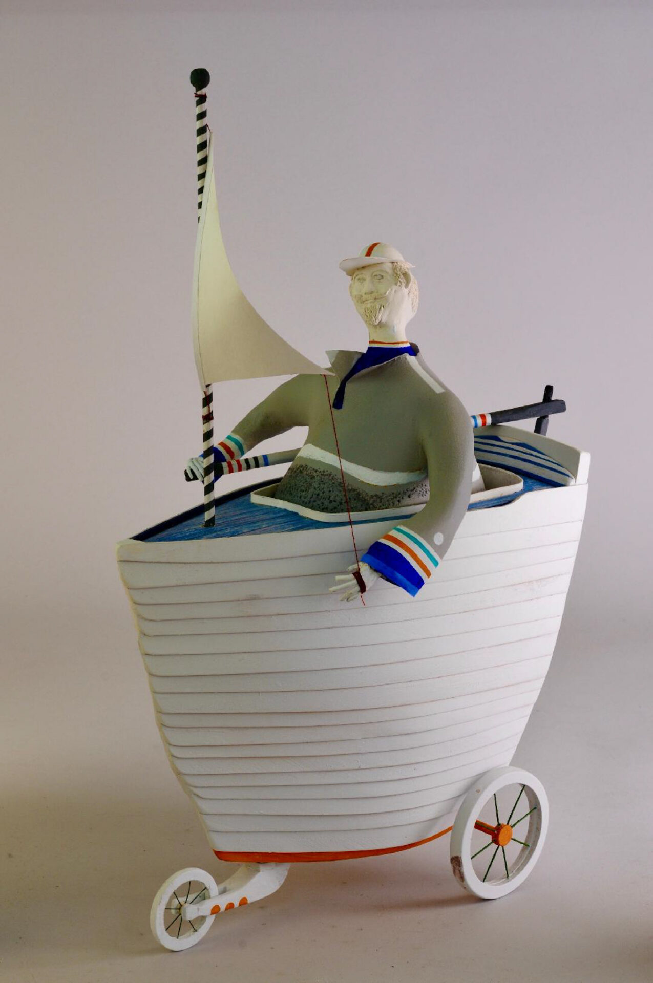 Whimsical sailor sculpture in wheeled boat