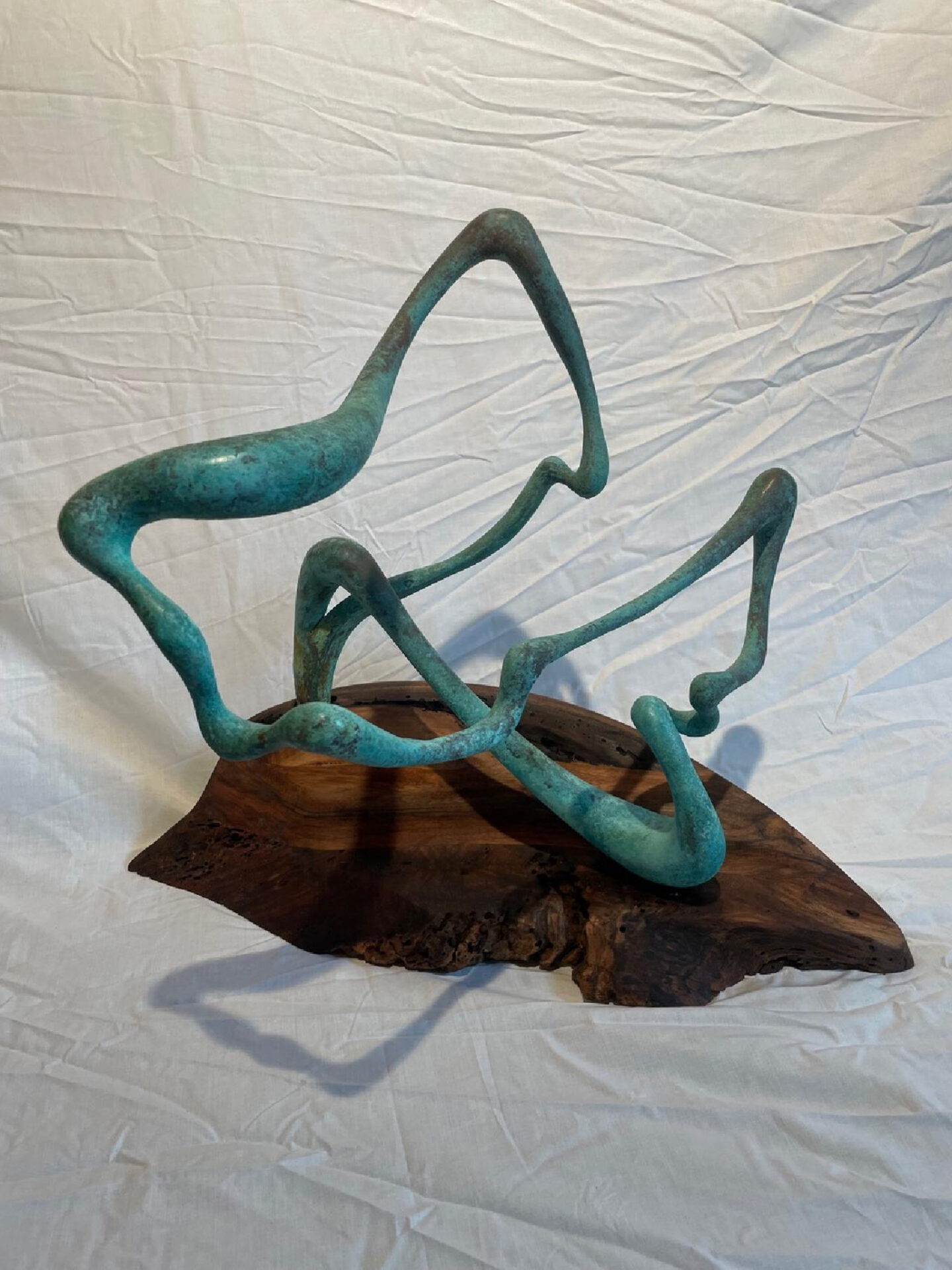 Abstract turquoise metal sculpture on wooden base